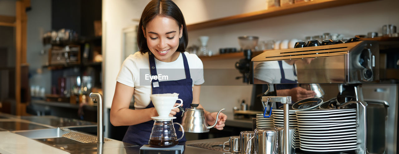 portrait of young woman using mobile phone while sitting in cafe