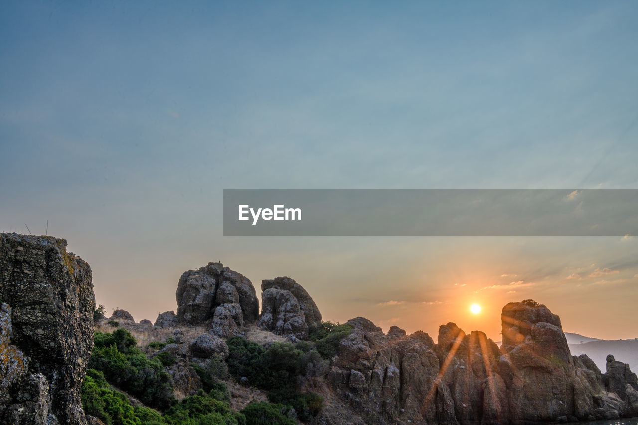 sky, rock, sunset, scenics - nature, nature, landscape, environment, beauty in nature, travel destinations, mountain, travel, cloud, land, rock formation, no people, tranquility, sun, outdoors, sea, tourism, horizon, tranquil scene, architecture, blue, cliff, dawn, non-urban scene, panoramic, dramatic sky, plant, sunlight, idyllic
