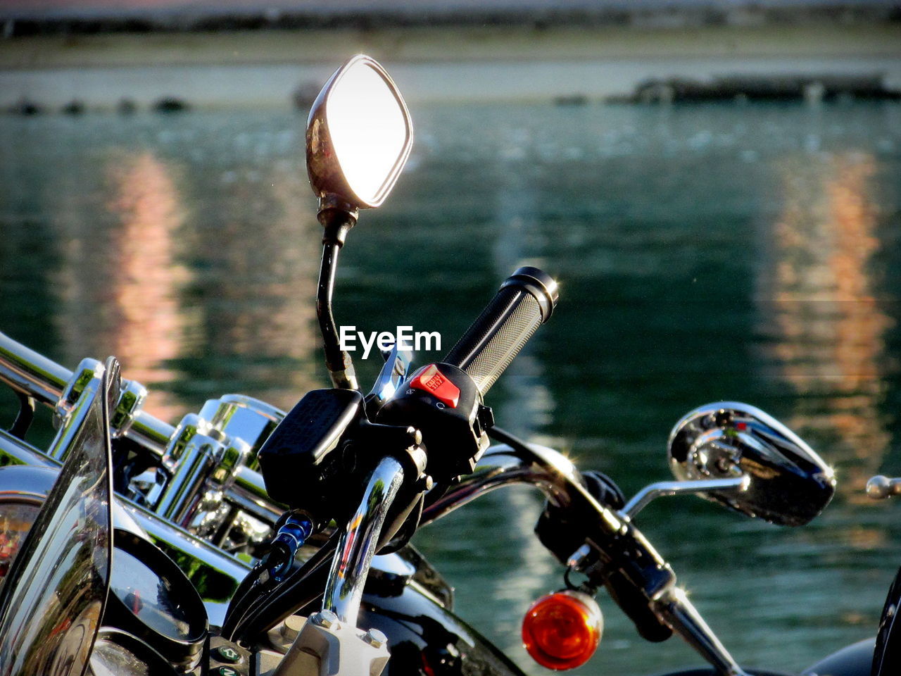 Mirror on motorcycle handlebar against river