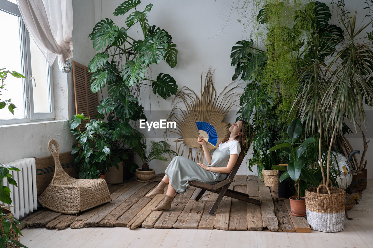 Stress relief after work. relaxed young girl spend time in cozy indoor garden with monstera plant