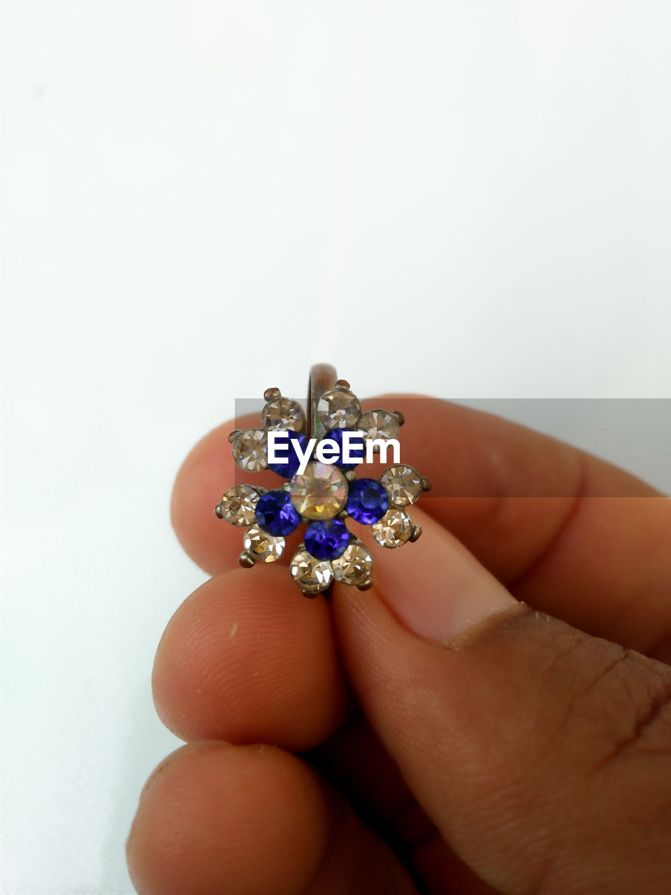 Close-up of hand holding ring against white background