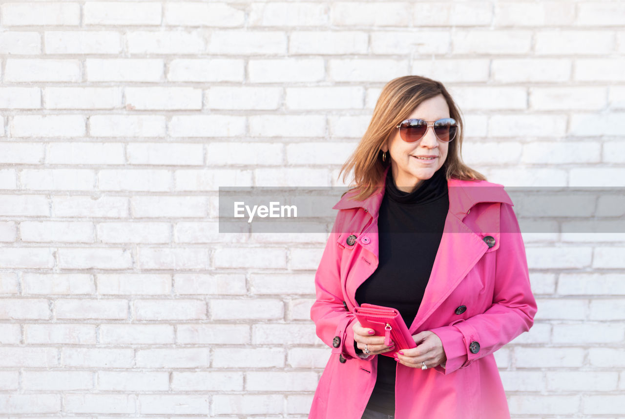 Woman in sunglasses standing against brick wall