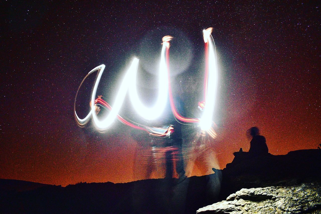 ILLUMINATED LIGHTING EQUIPMENT ON ROCK AGAINST SKY AT NIGHT