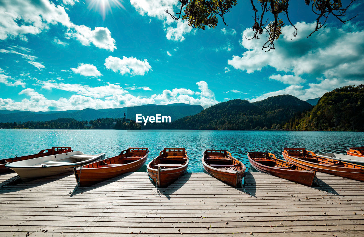 BOATS MOORED IN LAKE AGAINST MOUNTAINS