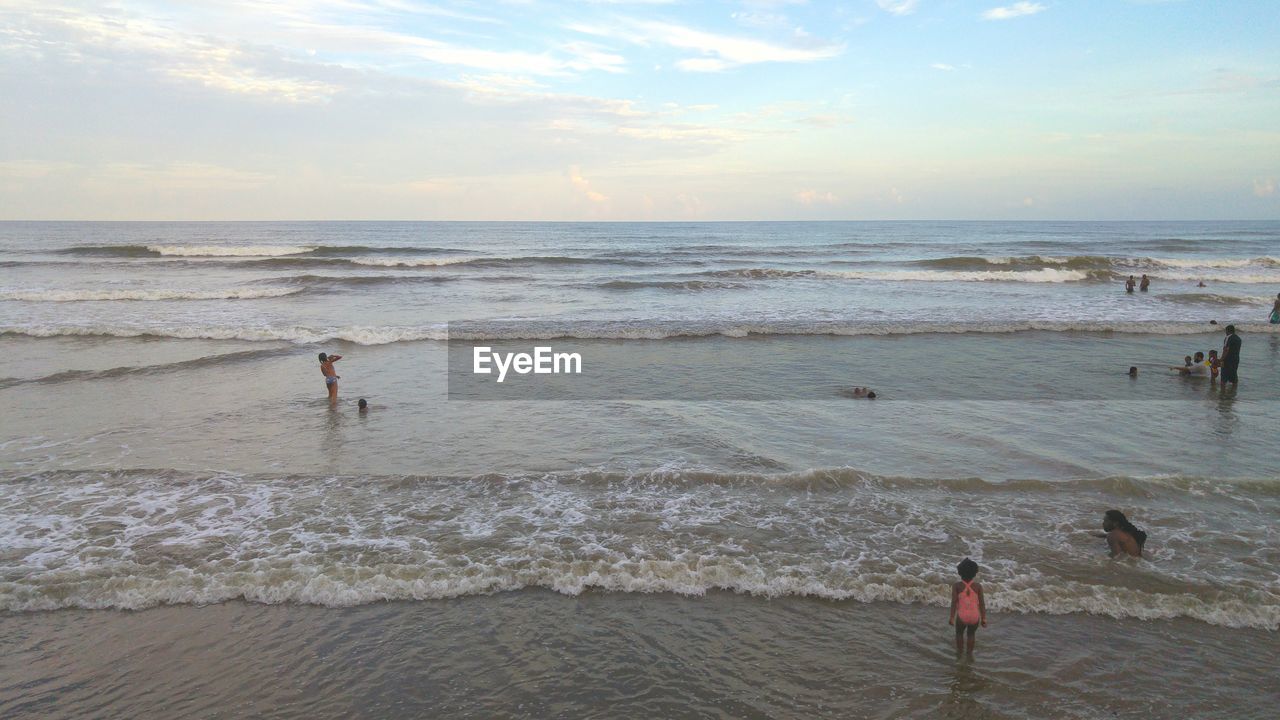 People enjoying on shore against sky