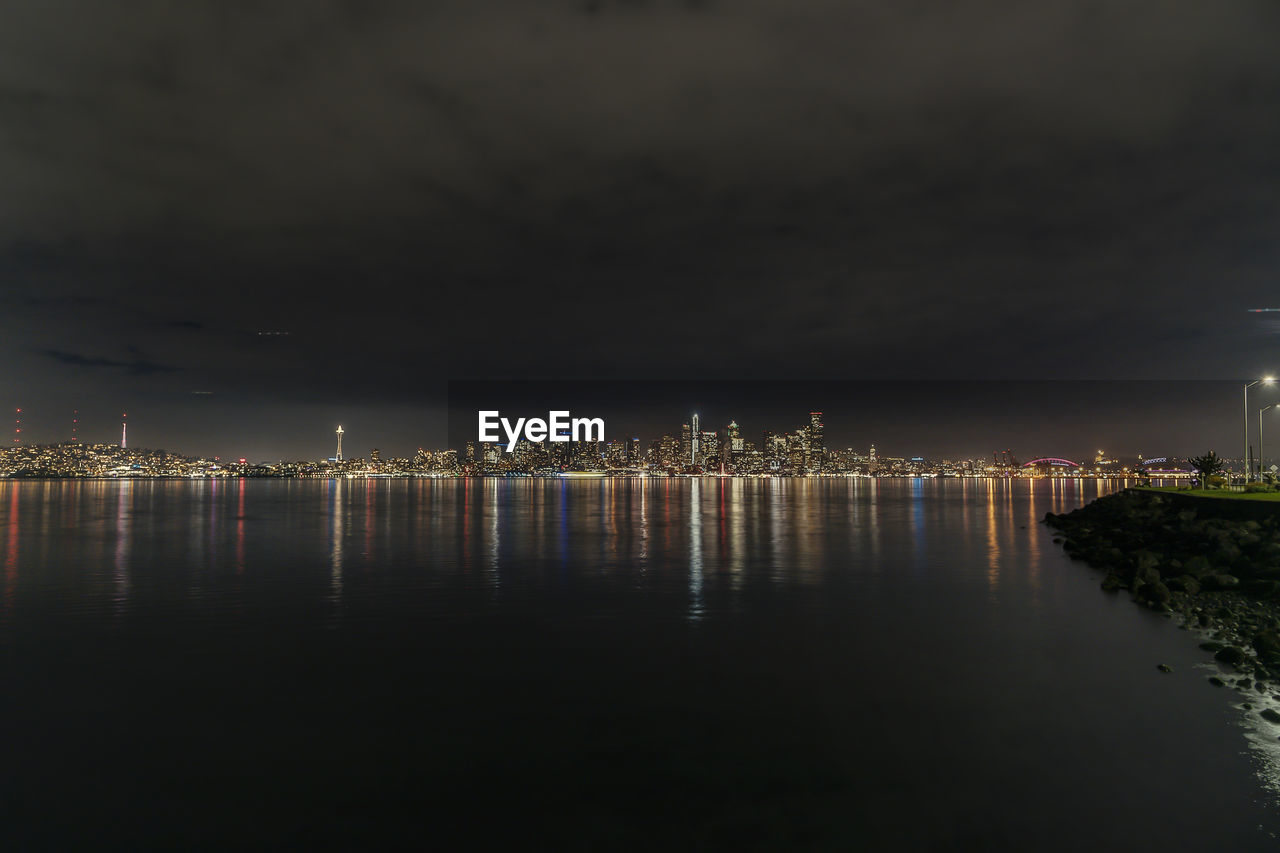 Long exposure seattle night skyline from west seattle with glowing night sky reflecting. 