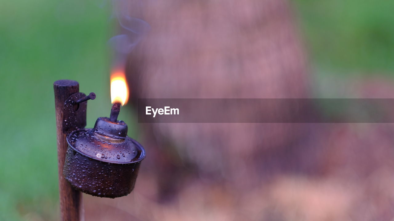 CLOSE-UP OF LIT CANDLES AGAINST METAL