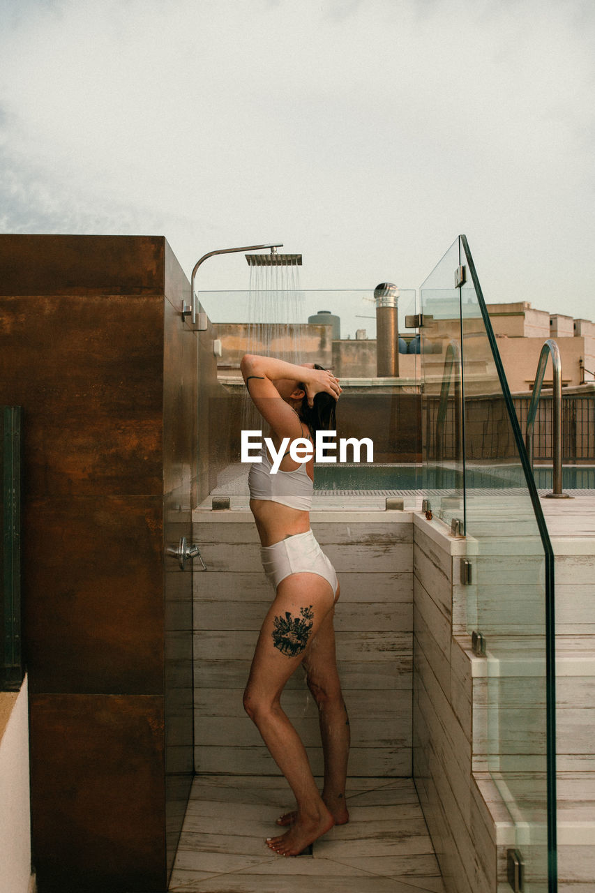 Woman standing by railing against sky