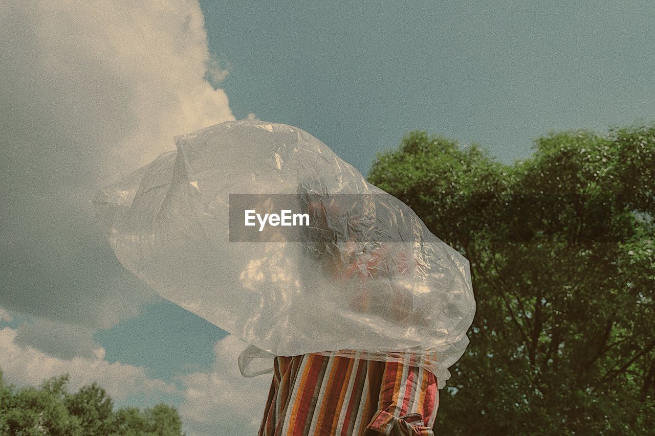 Man wearing plastic bag against sky