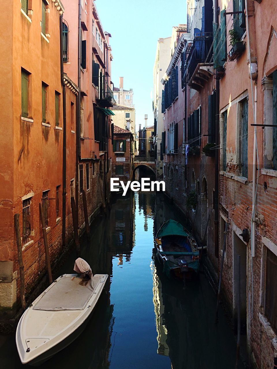 Boats moored in canal amidst buildings