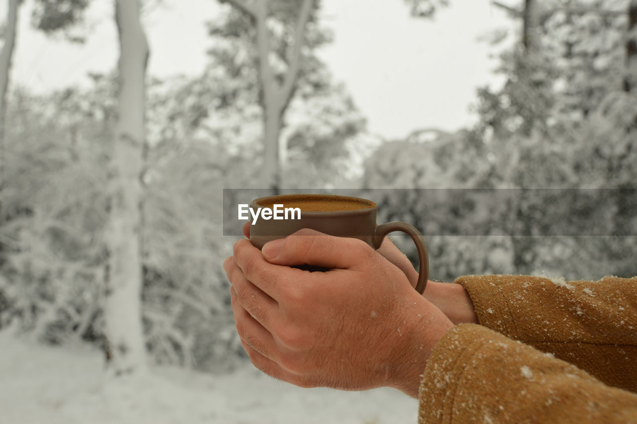 MAN HOLDING COFFEE CUP IN WINTER