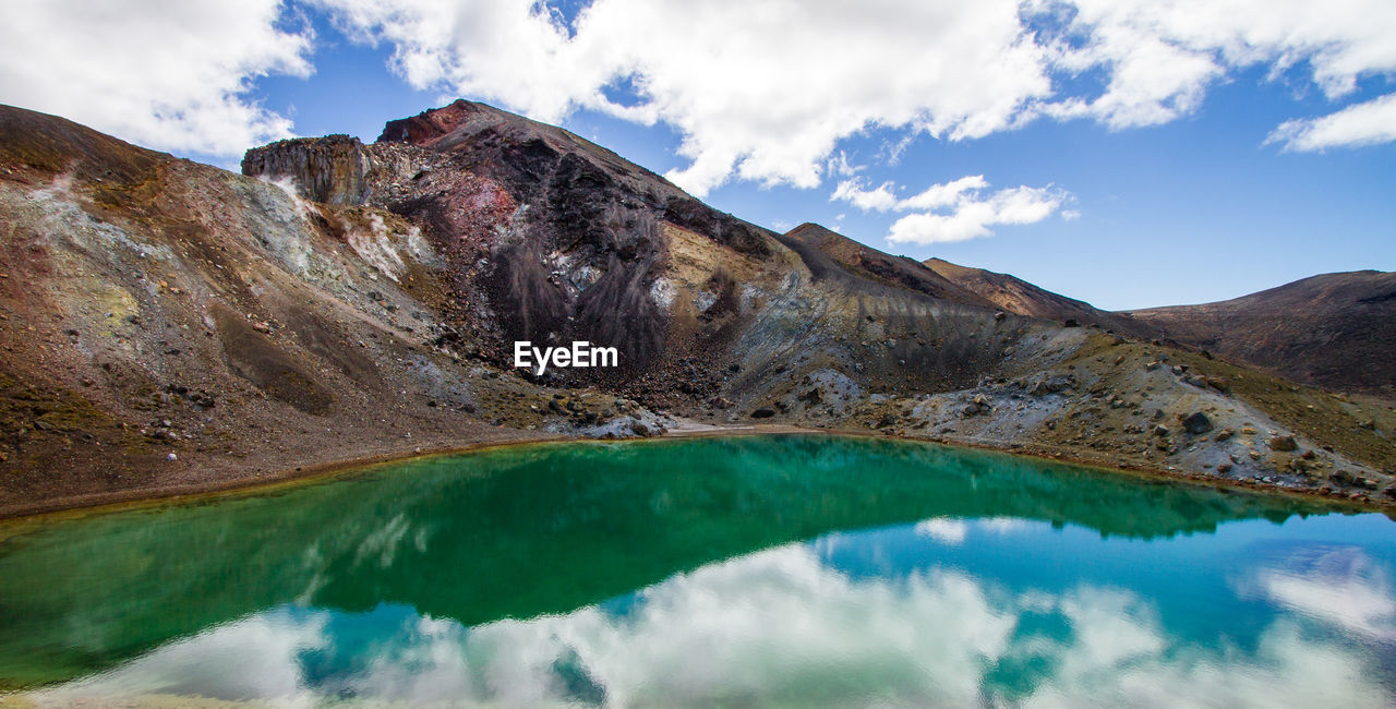 Rocky mountains reflecting in lake against sky