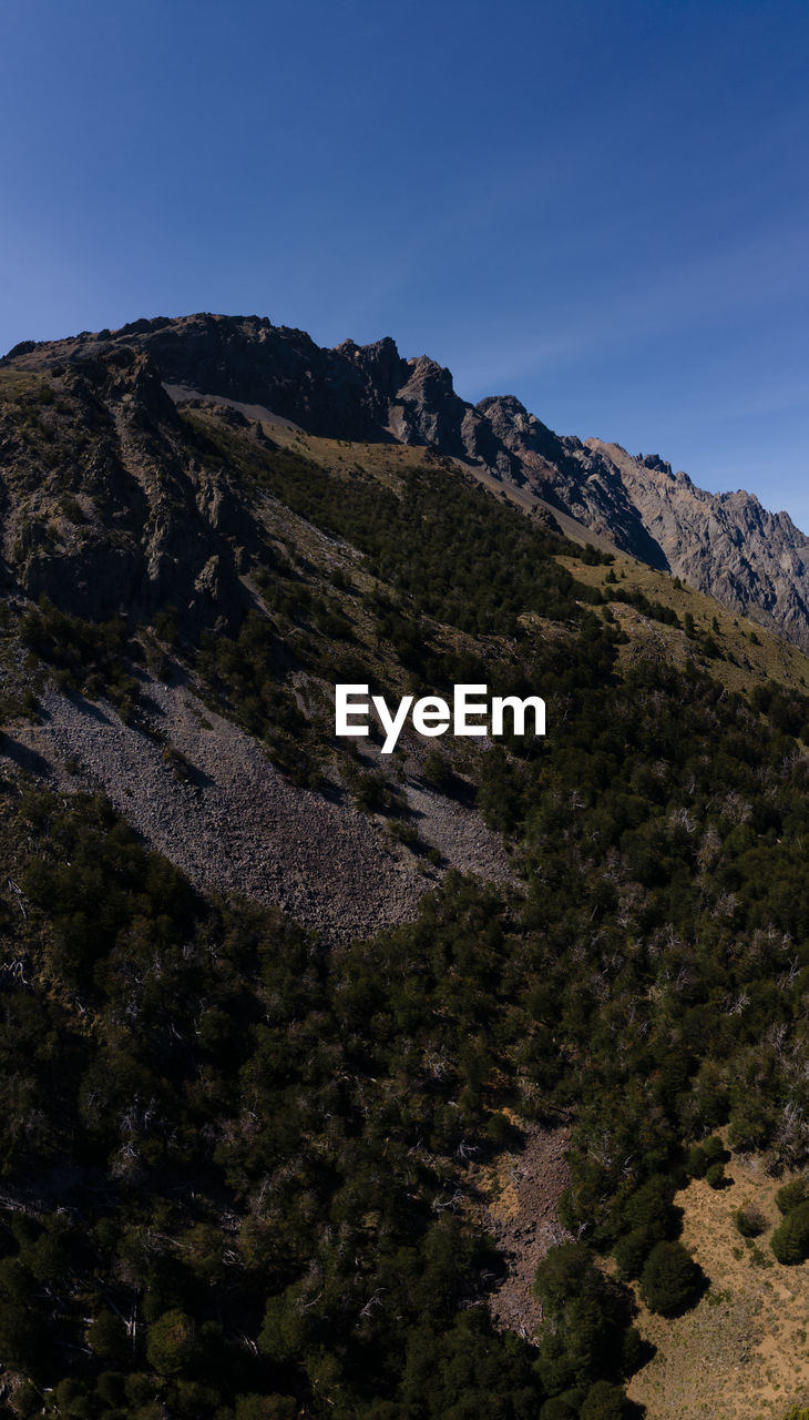 mountain, sky, nature, environment, wilderness, scenics - nature, landscape, beauty in nature, land, plant, tree, rock, travel destinations, no people, ridge, non-urban scene, travel, mountain range, outdoors, summit, tourism, clear sky, forest, tranquility, blue, coniferous tree, adventure, cloud, pinaceae, outdoor pursuit, pine tree, tranquil scene, animal wildlife, day, plateau, mountain peak