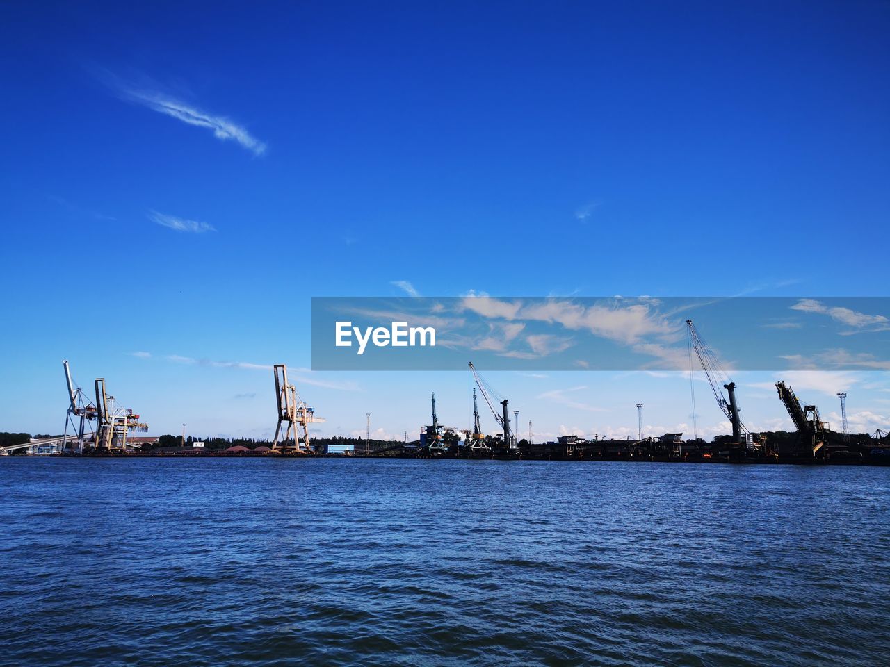 Commercial dock by sea against blue sky