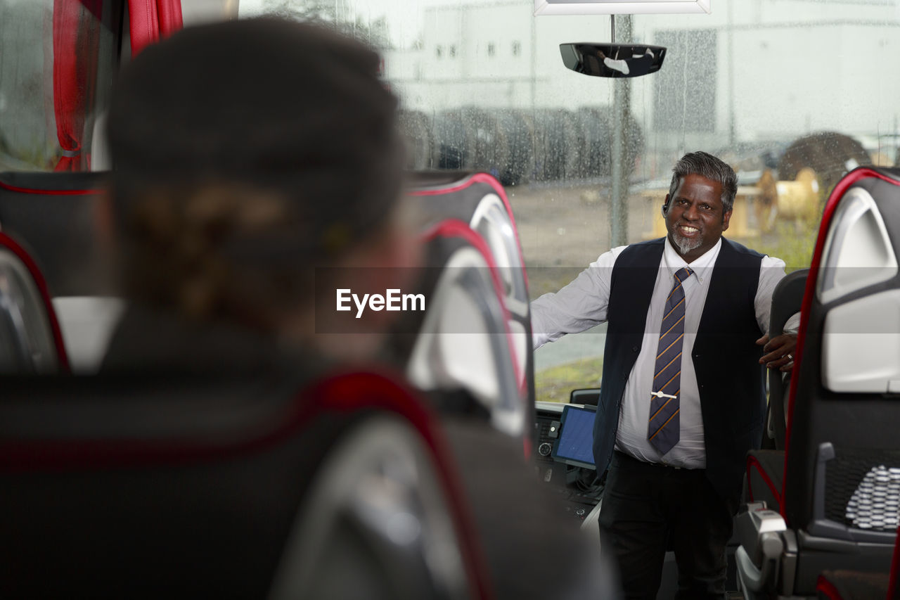 Smiling driver standing in bus