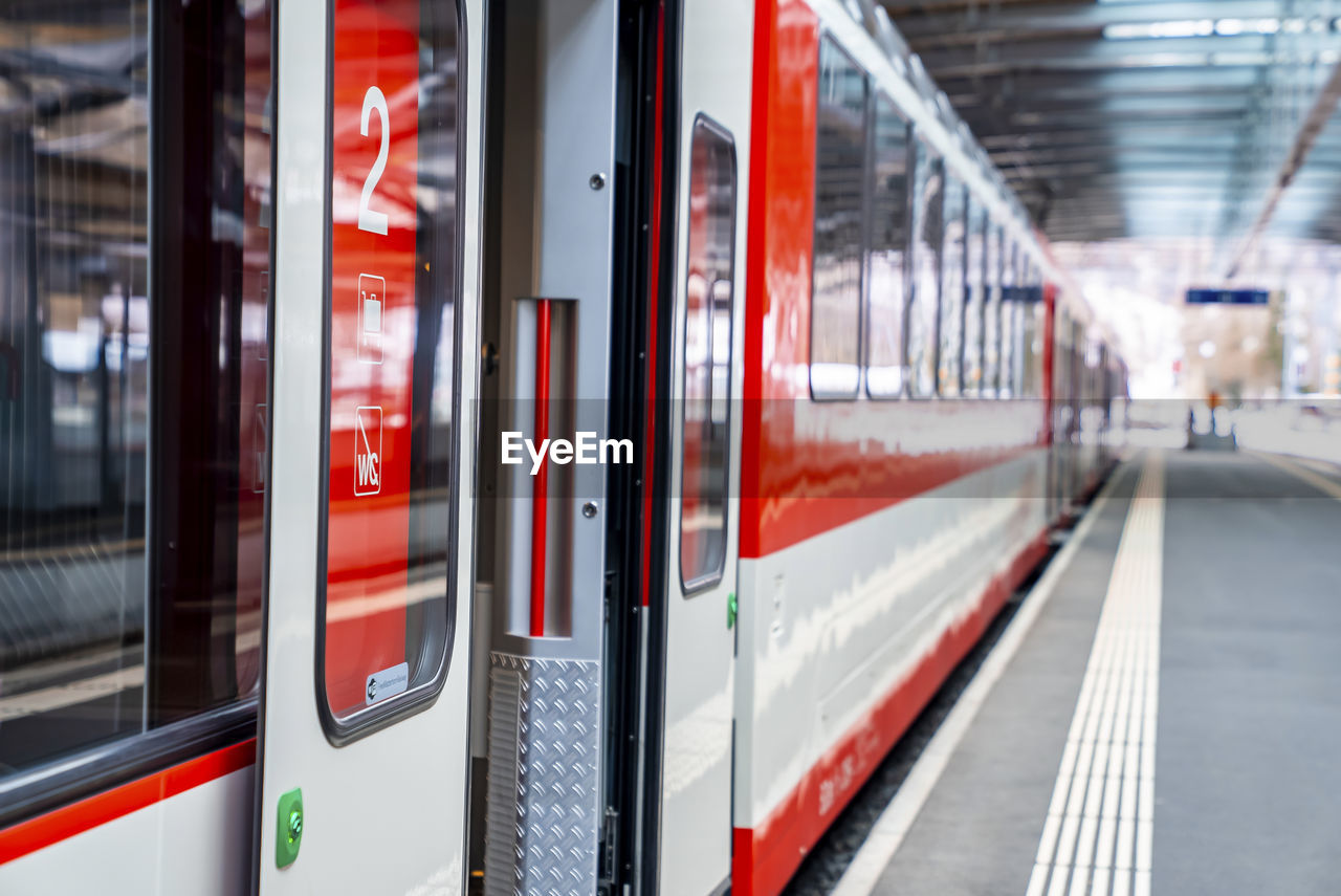 Open door of train arrived at platform on railroad station during sunny day