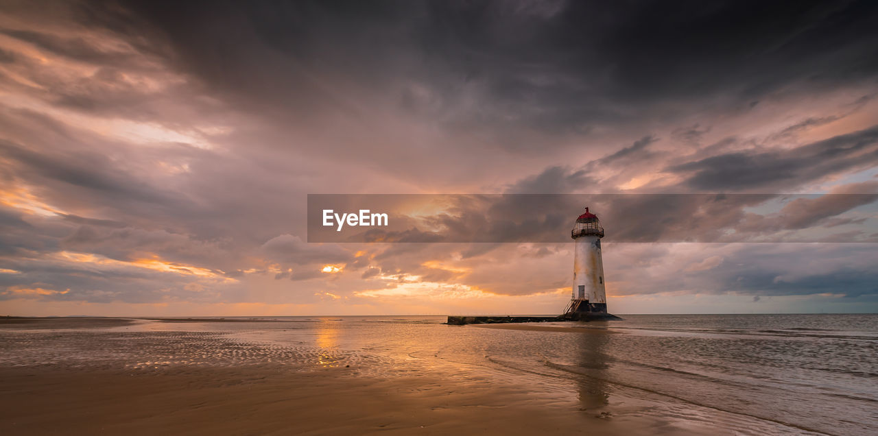 LIGHTHOUSE ON SEA AGAINST SKY DURING SUNSET