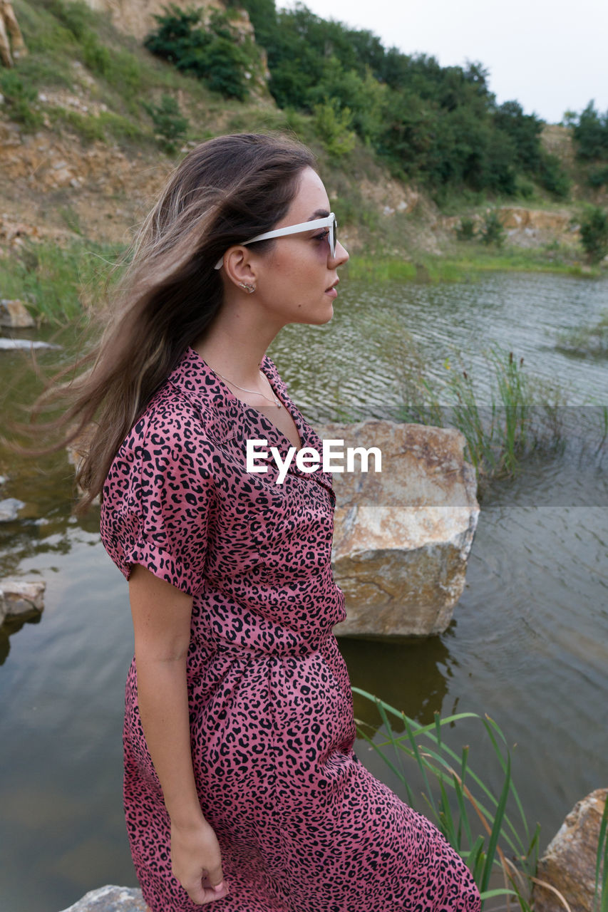 Young woman looking away while standing on rock