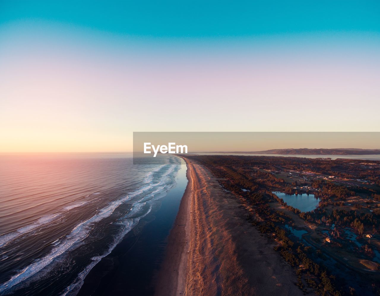 Road by sea against clear sky during sunset