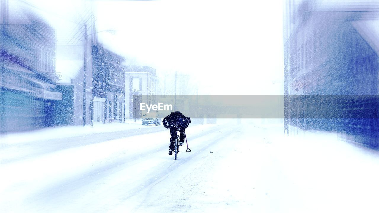 Person riding bicycle at street during snowy day