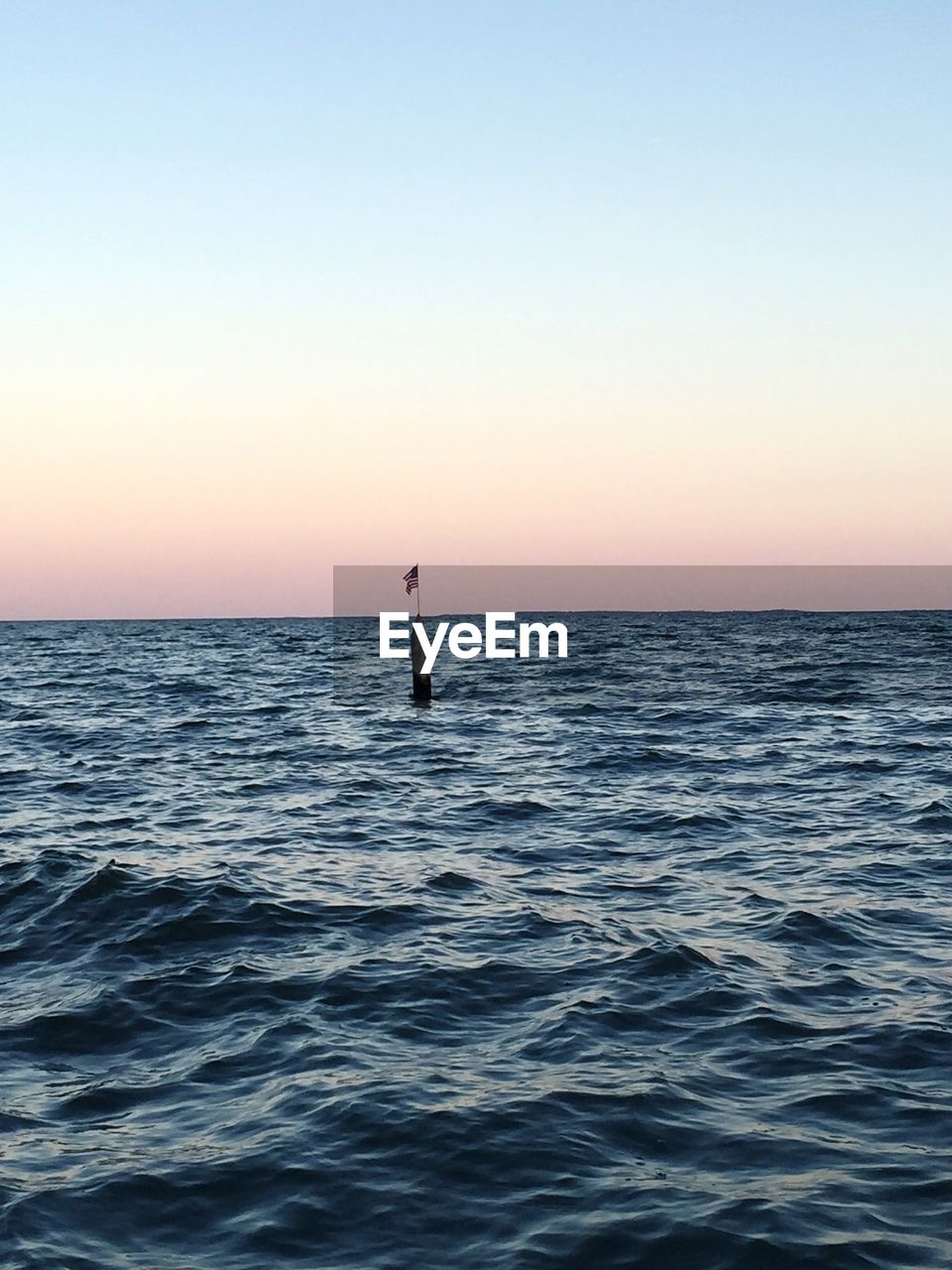 Silhouette man in sea against clear sky during sunset