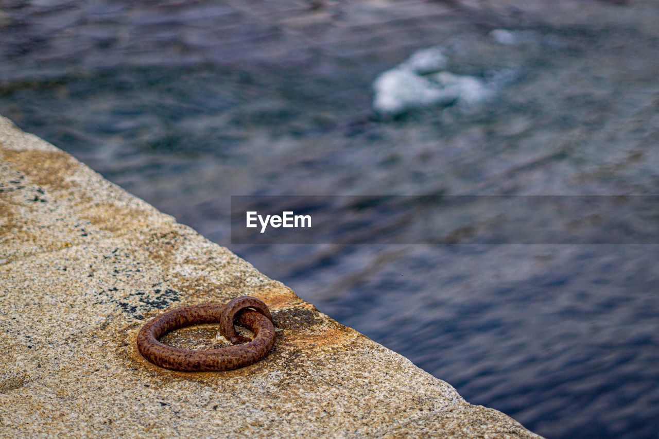 HIGH ANGLE VIEW OF RUSTY METAL BY SEA