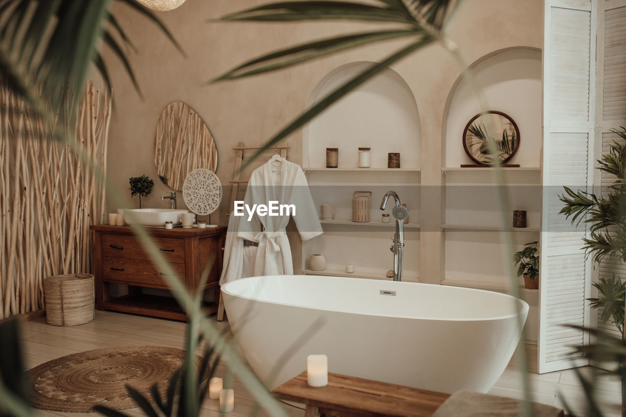 Luxury interior of big bathroom at modern african style with oval bathtub in natural lighting