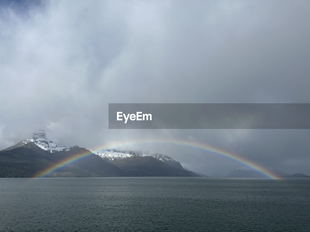 rainbow, cloud, beauty in nature, scenics - nature, water, environment, sky, mountain, nature, landscape, no people, cold temperature, storm, horizon, tranquility, sea, natural phenomenon, tranquil scene, travel destinations, winter, snow, dramatic sky, day, travel, outdoors, overcast, land, storm cloud, non-urban scene, idyllic, rain, multi colored, tourism, mountain range, wet, fog