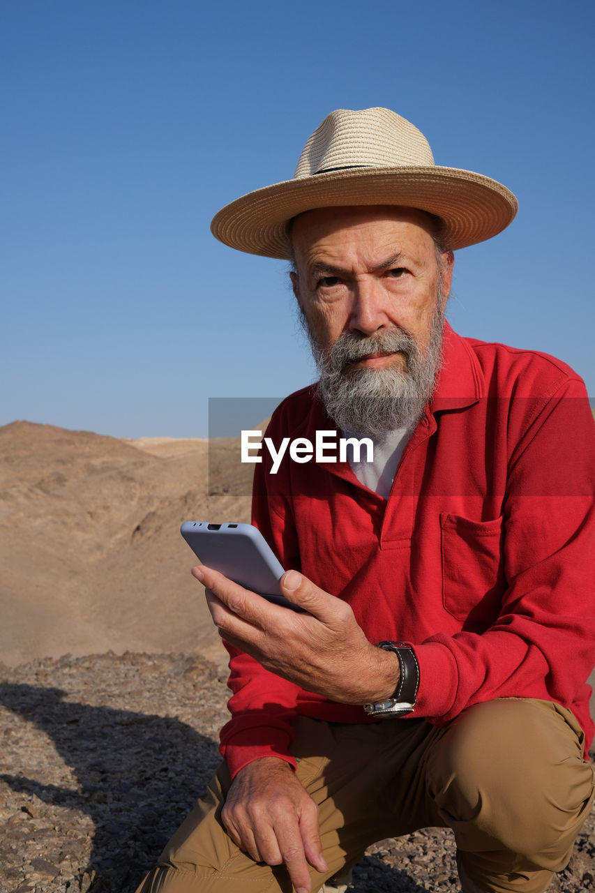 Vertical view of senior man using mobile phone in the desert 