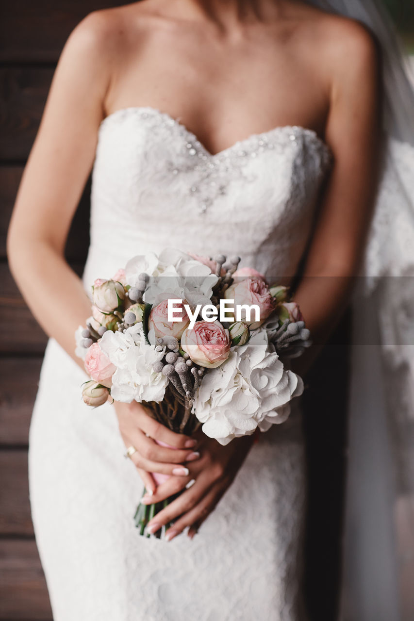 midsection of bride holding flower bouquet