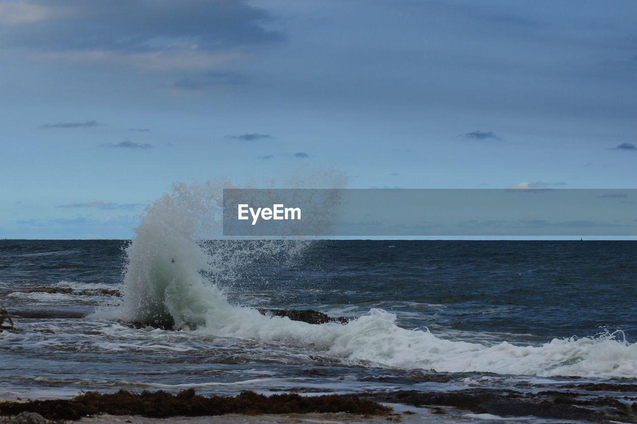 VIEW OF WAVES BREAKING AGAINST SKY