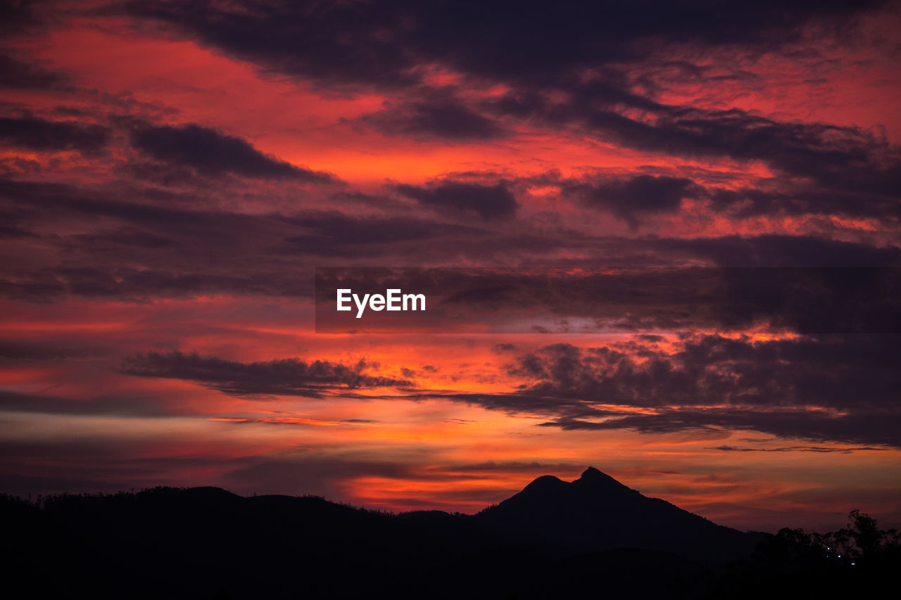 Scenic view of silhouette mountains against orange sky