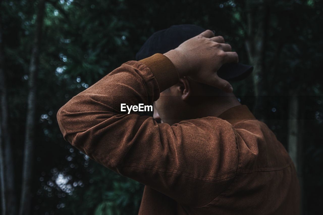 Close-up of young man standing against trees