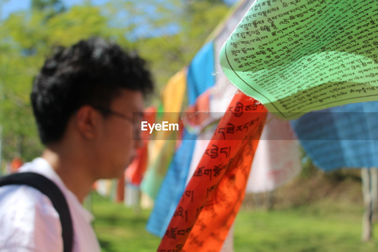 Close-up of prayer flags with man in background