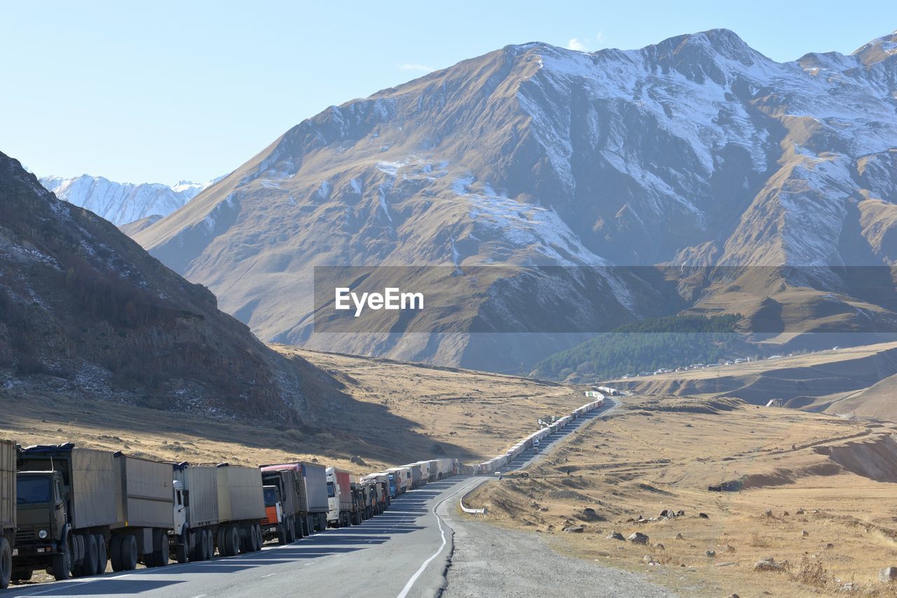 Trucks on road leading towards mountain during winter