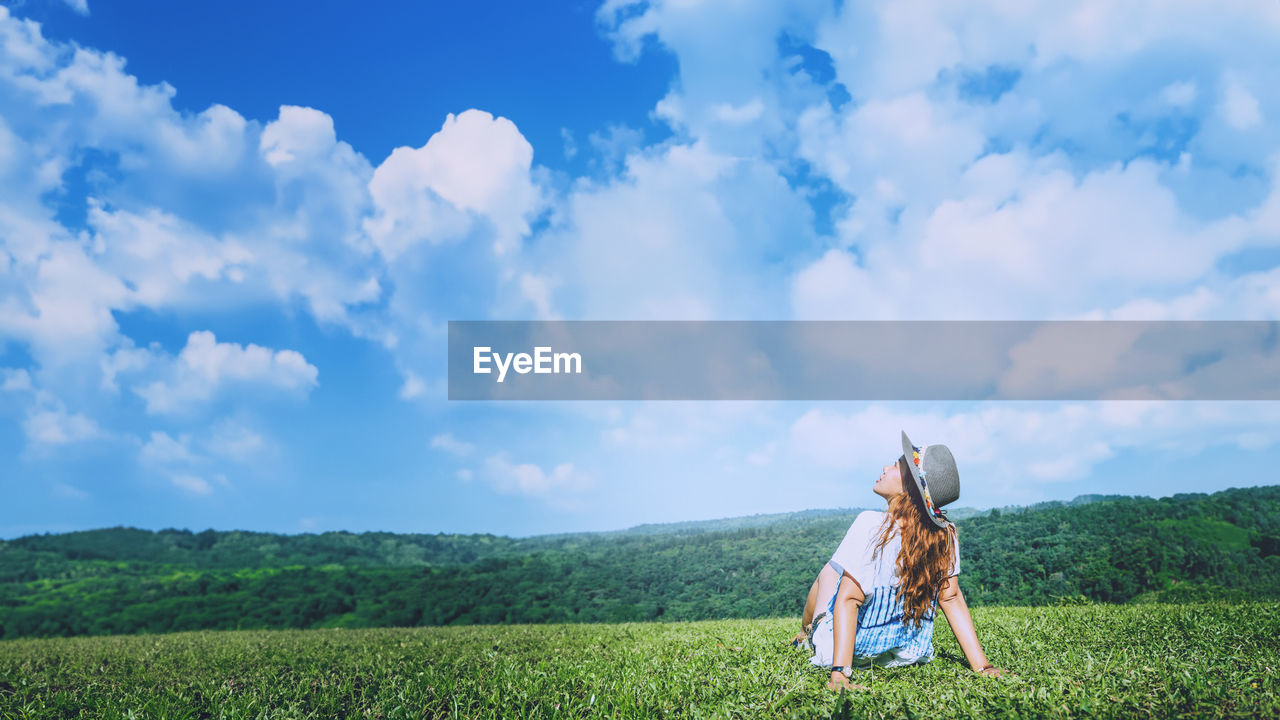 rear view of woman standing on grassy field against sky