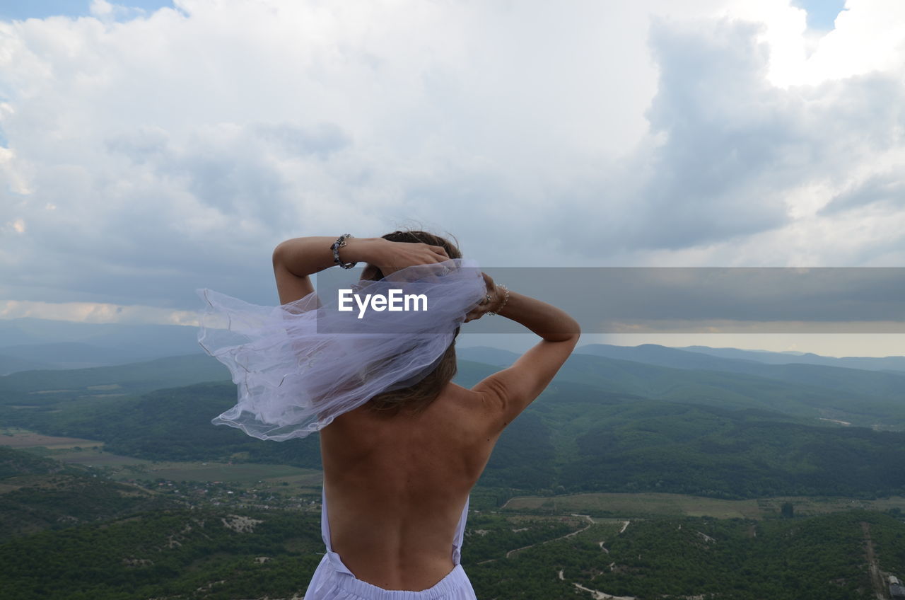 Midsection of woman standing on mountain against sky