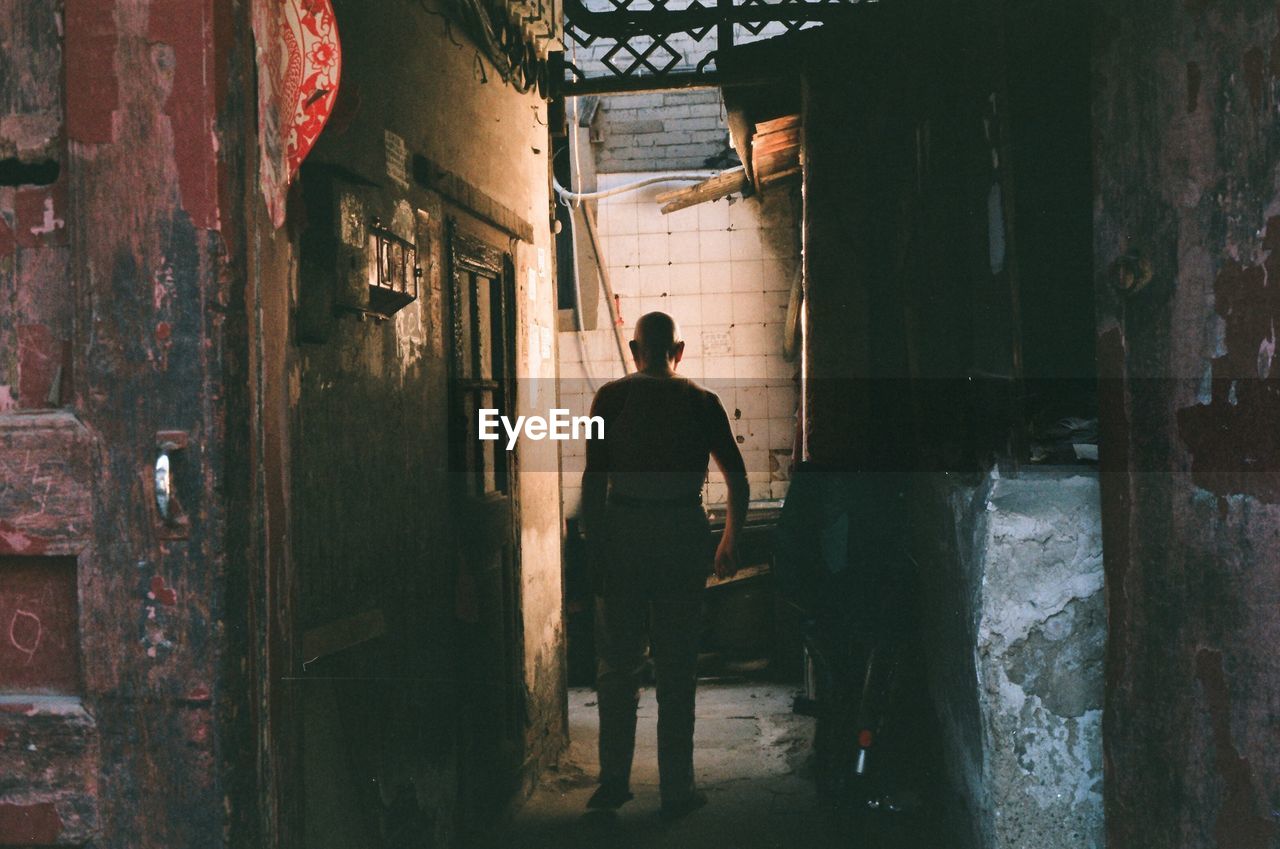 FULL LENGTH REAR VIEW OF MAN WALKING IN BUILDING