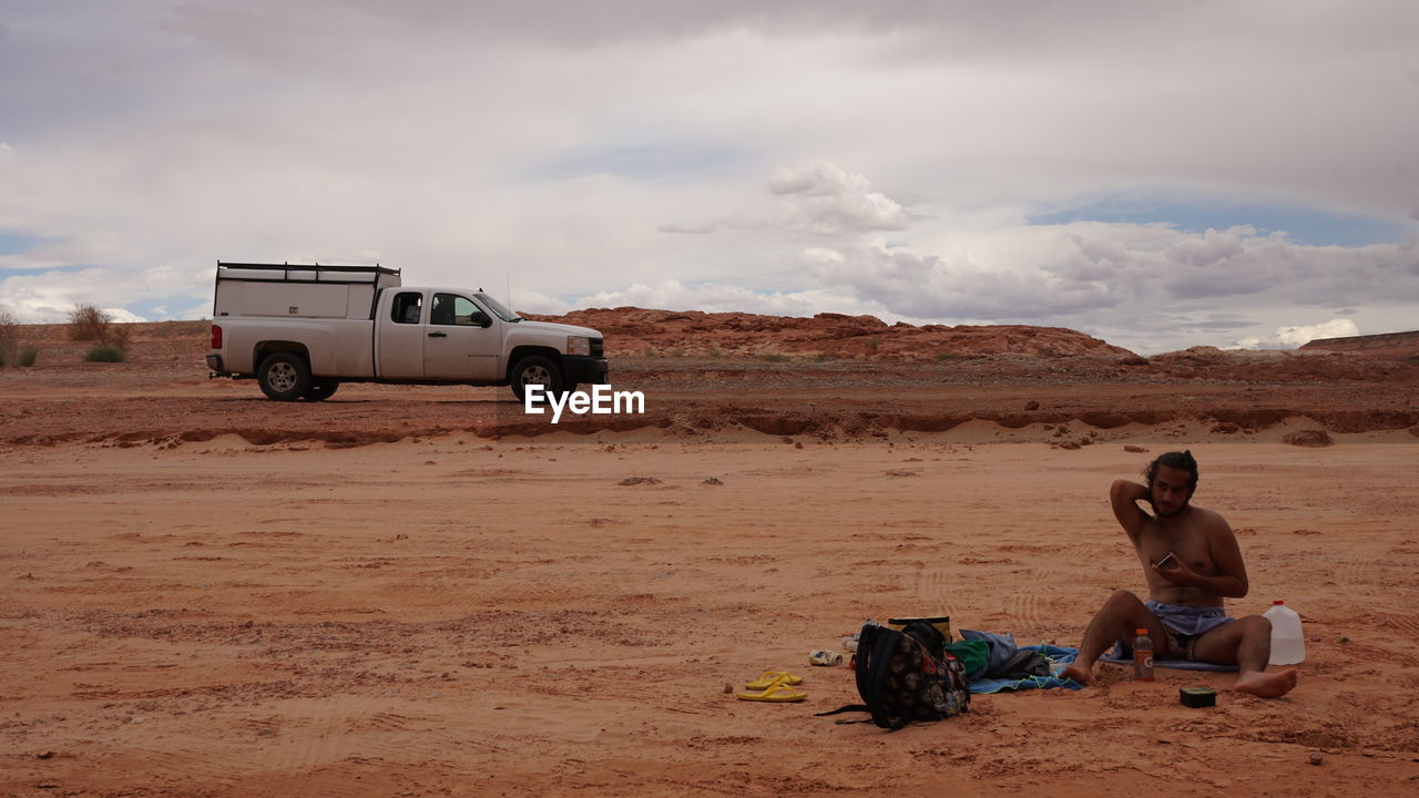 FULL LENGTH OF WOMAN SITTING ON SAND