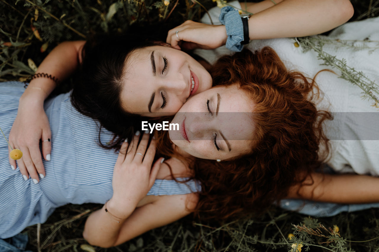 HIGH ANGLE PORTRAIT OF YOUNG WOMAN LYING ON GRASS