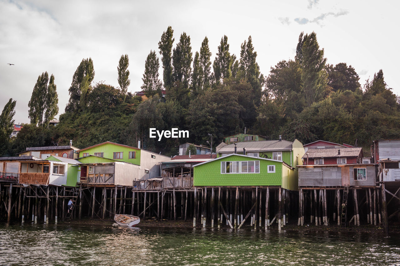 Stilt houses by lake against trees