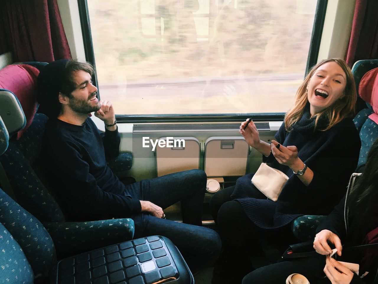 Happy friends sitting in train