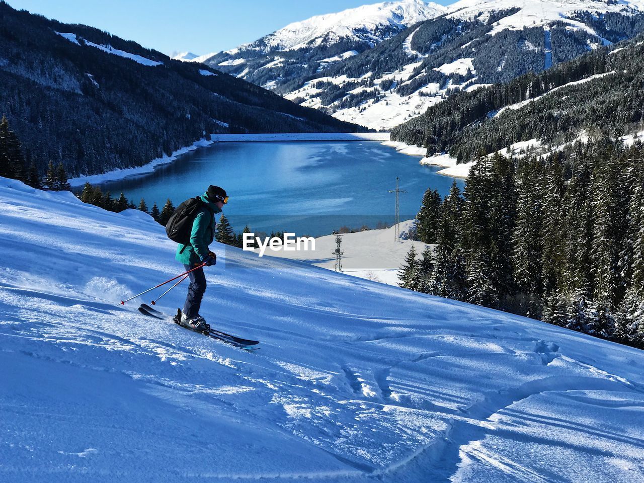 Young man skiing downhill on snowcapped mountain