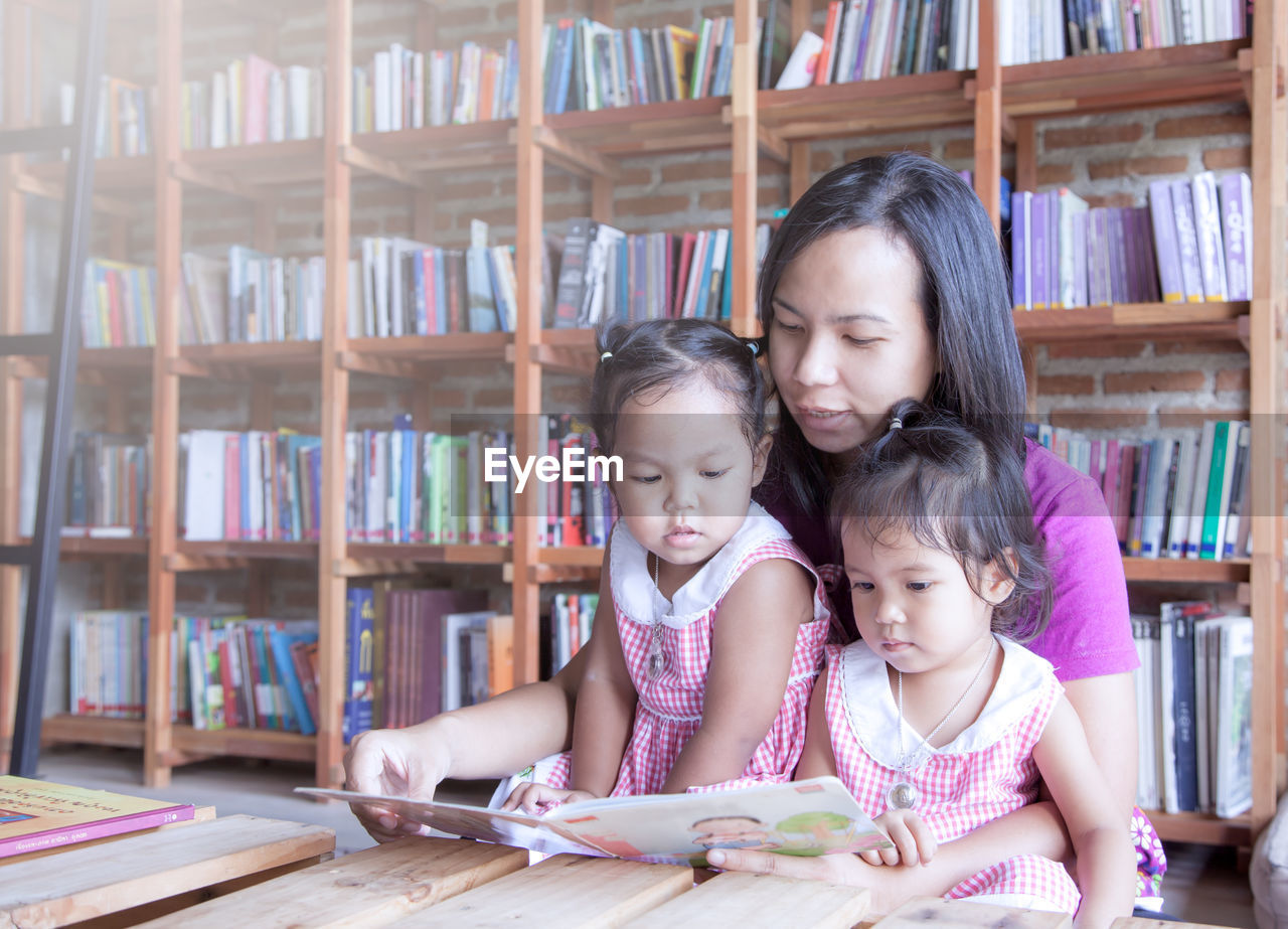 Mother showing book to daughters at home