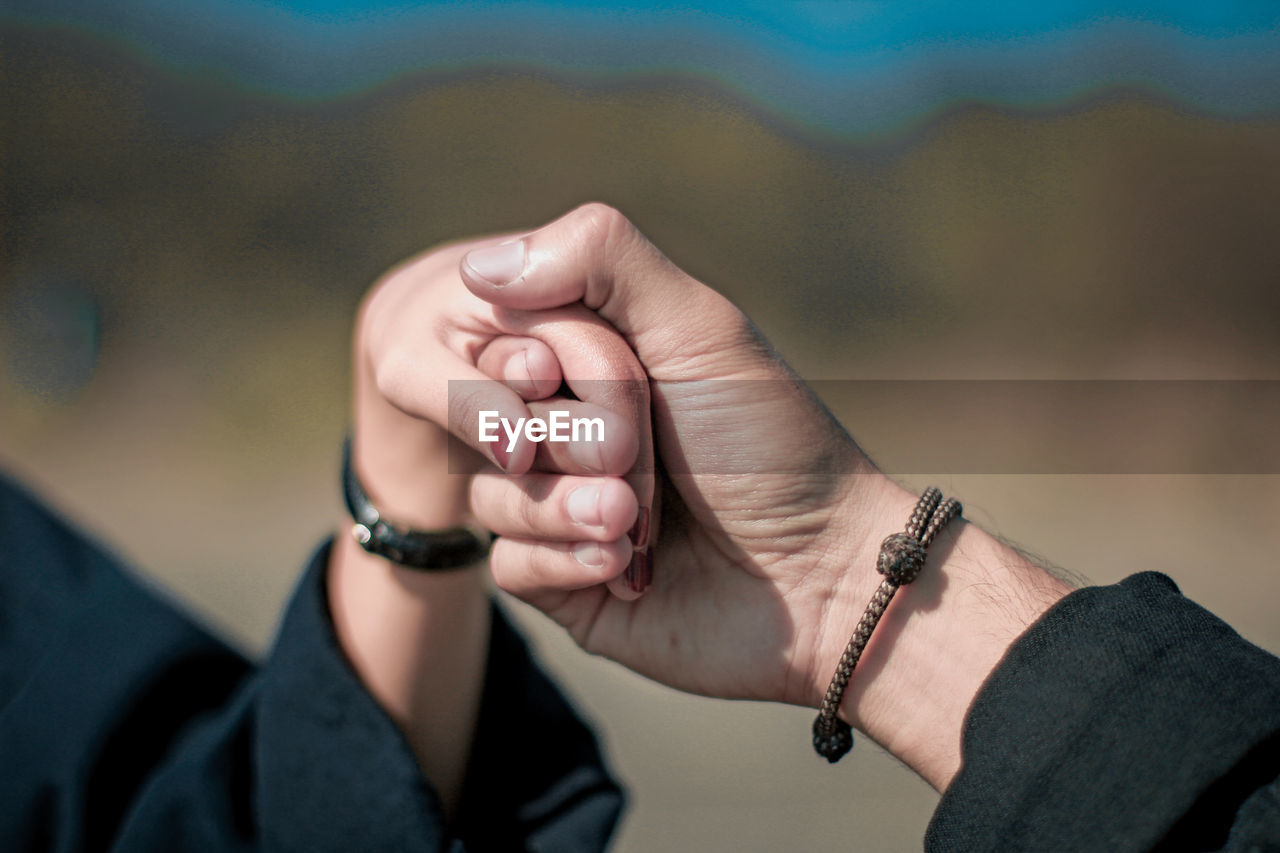 Cropped image of couple holding hands outdoors