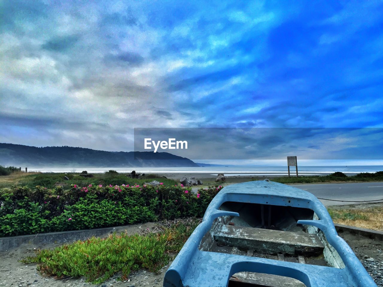 Boat moored in front of sea against cloudy blue sky