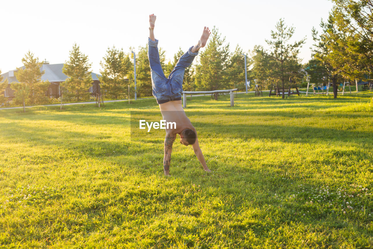 FULL LENGTH OF MAN JUMPING ON GRASS