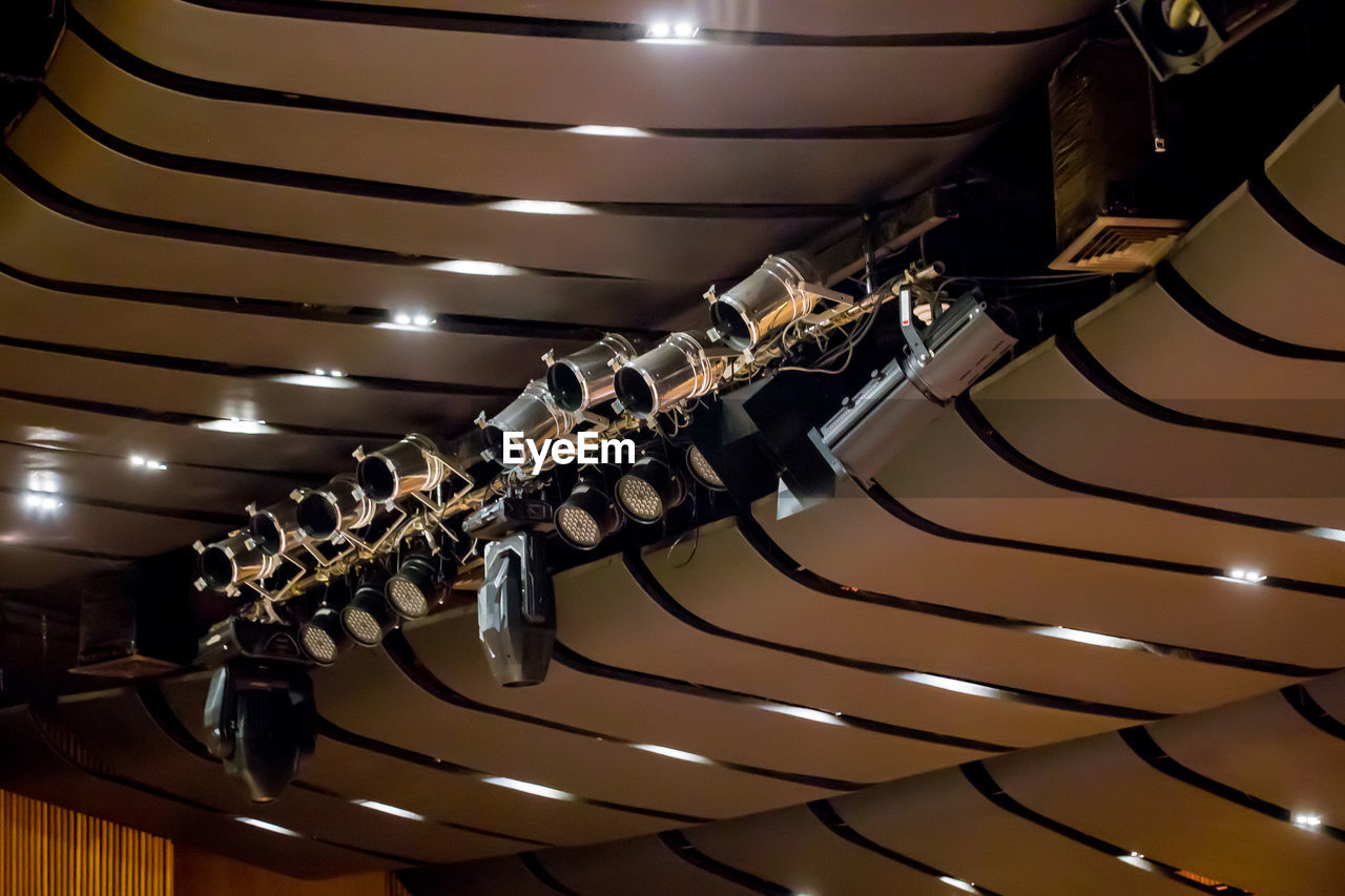 LOW ANGLE VIEW OF ILLUMINATED LIGHTING EQUIPMENT HANGING IN CEILING