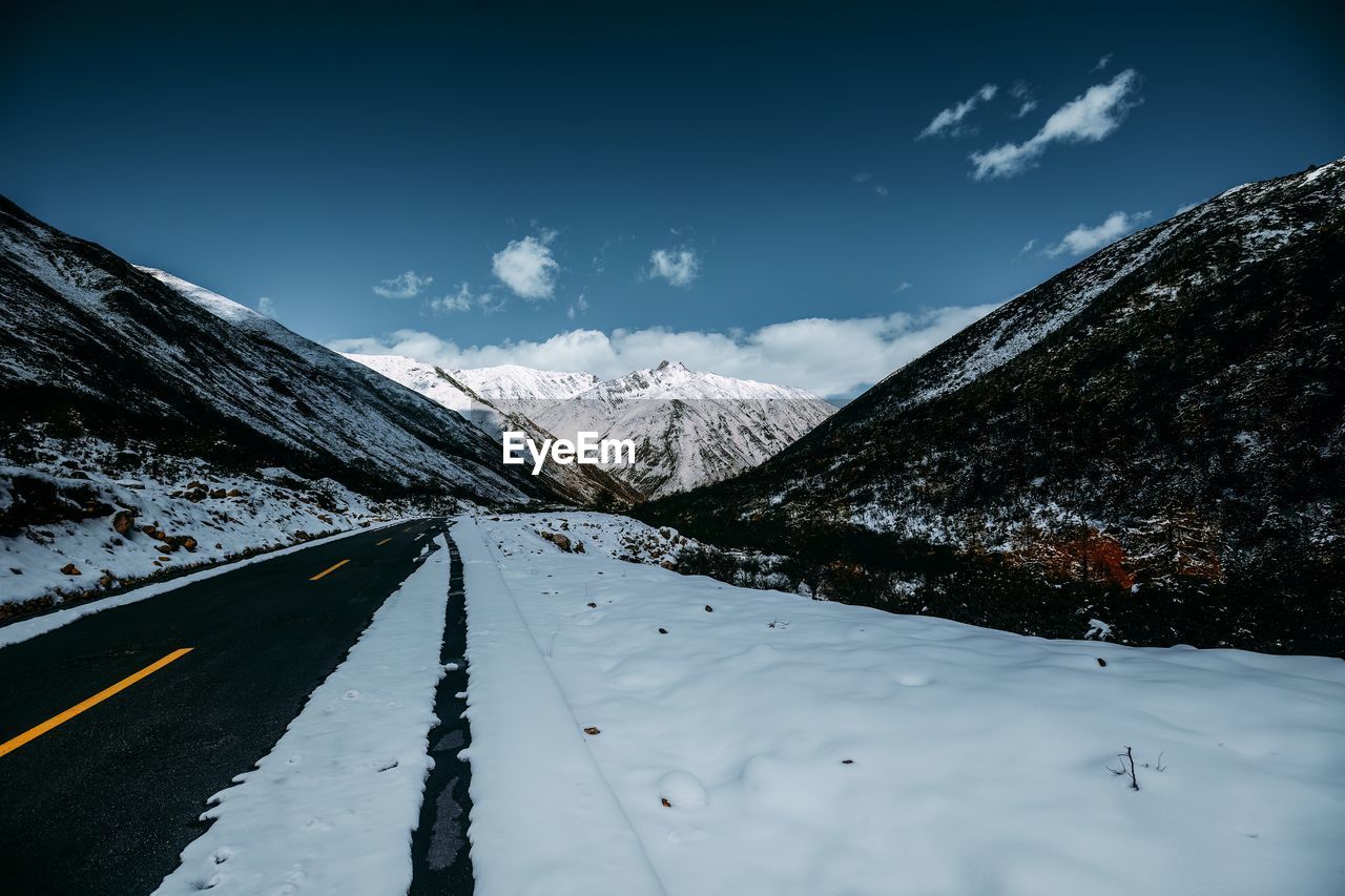 road amidst snowcapped mountains against sky