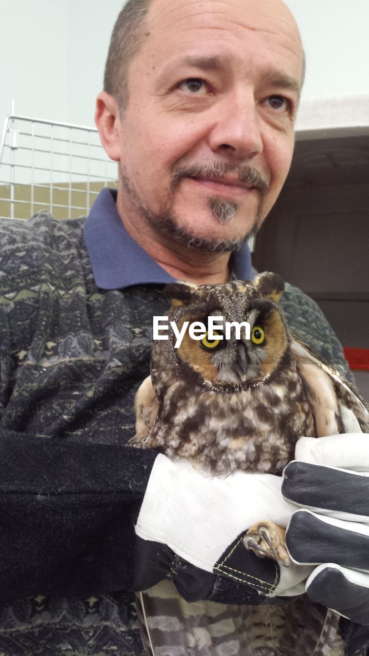Mature man with owl standing outdoors
